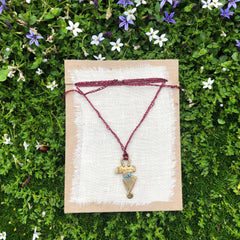 adjustable necklace: yellow bronze charm wrapped with indigo-dyed silk thread on burgundy crocheted cord