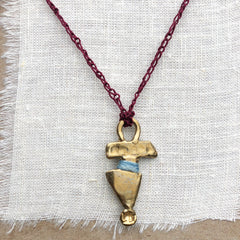 adjustable necklace: yellow bronze charm wrapped with indigo-dyed silk thread on burgundy crocheted cord