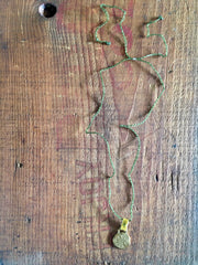 necklace: yellow bronze charm with green cord