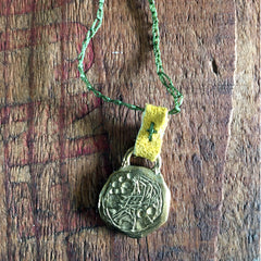 necklace: yellow bronze charm with green cord