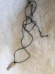 adjustable necklace: yellow bronze charm wrapped with indigo-dyed silk thread on dark brown crocheted cord