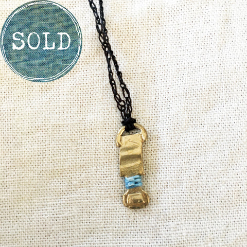 adjustable necklace: yellow bronze charm wrapped with indigo-dyed silk thread on dark brown crocheted cord